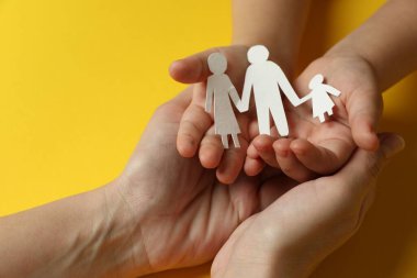 Mani adulte e bambine che tengono insieme una famiglia di carta